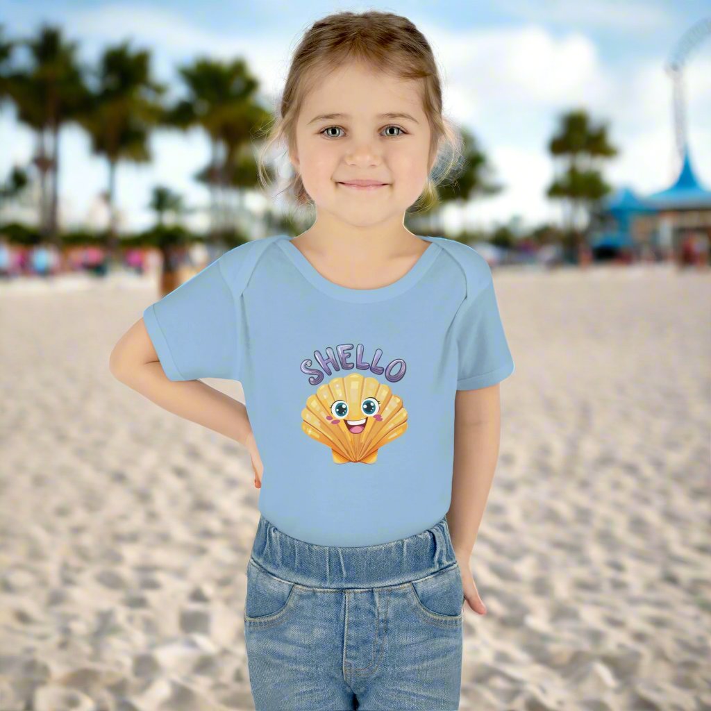 Cute little girl standing on a beach striking a sassy pose wearing a onesie with a funny shell saying SHello.