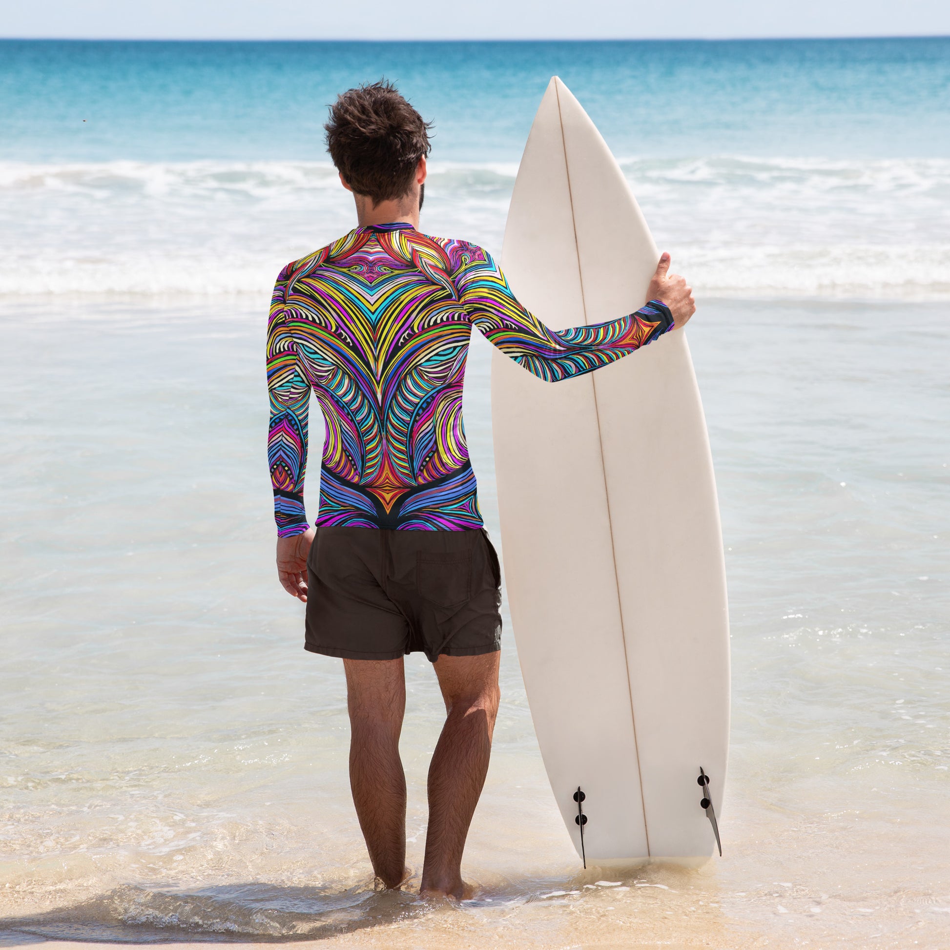 Man in colorful rash guard holding a surfboard on the beach, ready for fun in the sun with UPF 50+ protection.