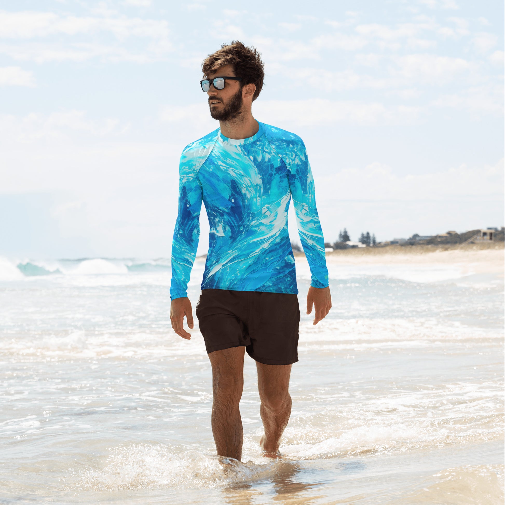 Man in a vibrant blue wave-pattern rash guard walking on the beach, ready for surfing and sun protection.