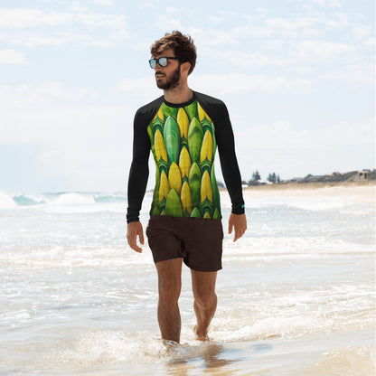 Man in a colorful surfboard-patterned rash guard walking on the beach, enjoying the waves.